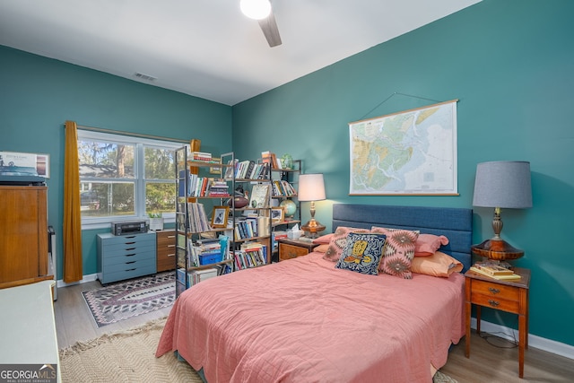 bedroom featuring ceiling fan, visible vents, baseboards, and wood finished floors