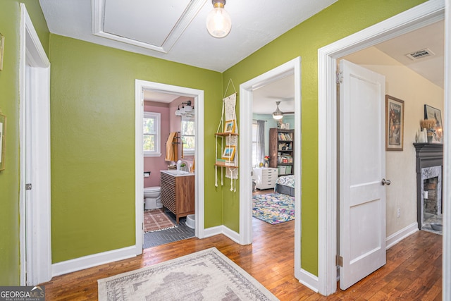 hall with visible vents, baseboards, and wood finished floors