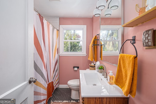 bathroom with vanity, toilet, a shower with curtain, and baseboards