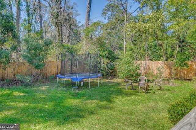 view of yard featuring a trampoline and fence