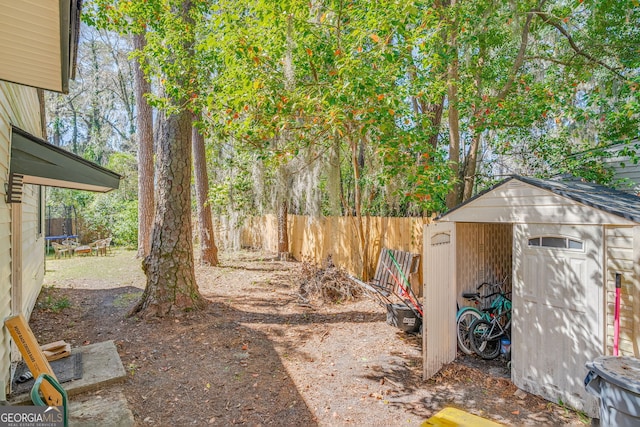 view of yard featuring an outbuilding, a fenced backyard, a storage unit, and a trampoline