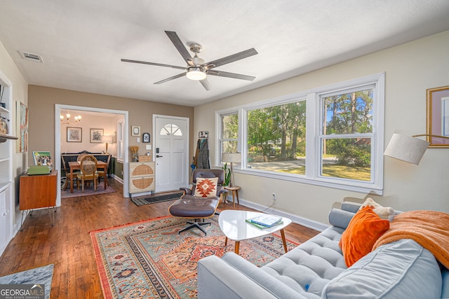 living room featuring visible vents, ceiling fan with notable chandelier, baseboards, and hardwood / wood-style flooring