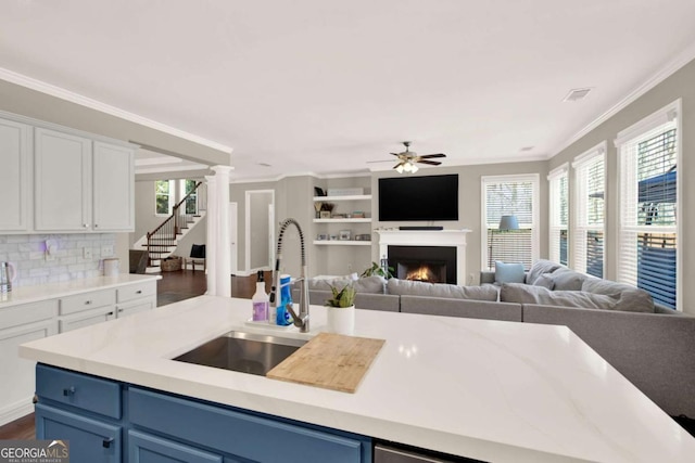 kitchen featuring ceiling fan, blue cabinets, open floor plan, and a sink