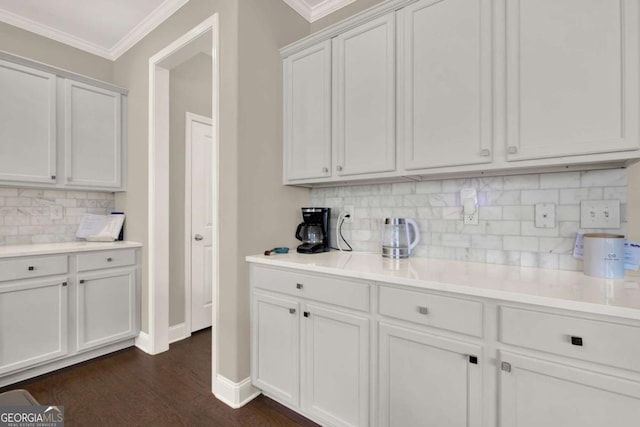 kitchen featuring decorative backsplash, light countertops, crown molding, and dark wood-type flooring