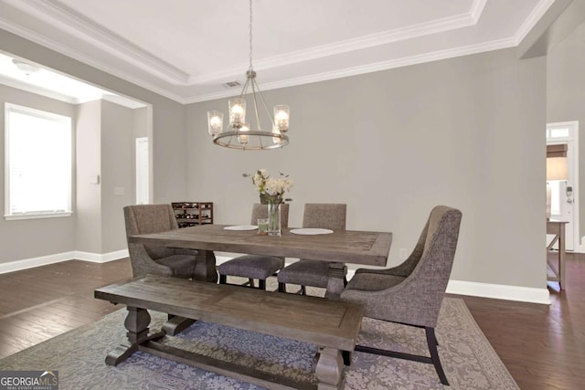 dining room featuring a notable chandelier, a raised ceiling, wood-type flooring, crown molding, and baseboards