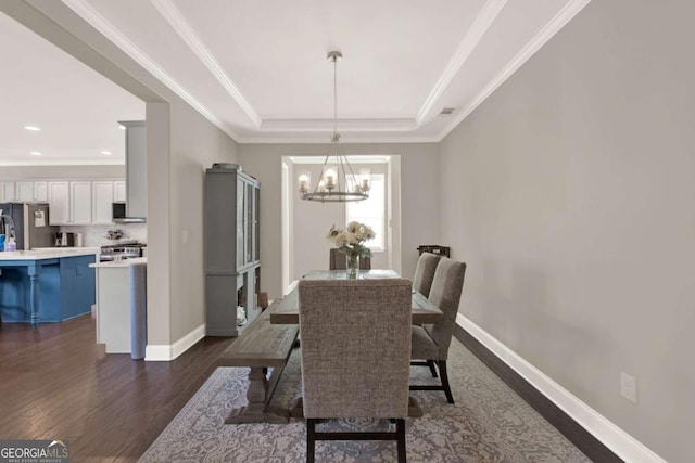 dining space featuring a chandelier, baseboards, dark wood-type flooring, and a tray ceiling