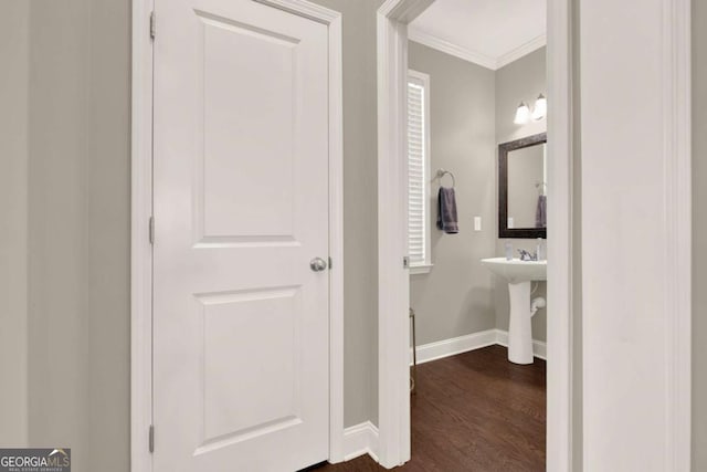 bathroom with a sink, crown molding, baseboards, and wood finished floors