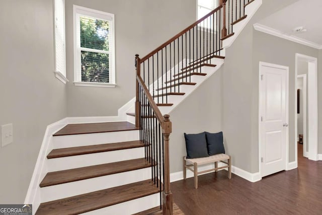 stairs featuring crown molding, wood finished floors, and baseboards