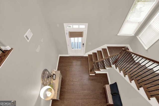 foyer entrance with baseboards, wood finished floors, and stairs