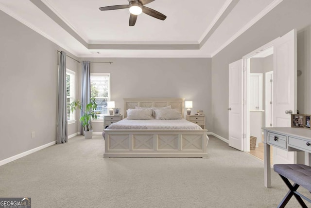 bedroom featuring a tray ceiling, baseboards, light colored carpet, and crown molding