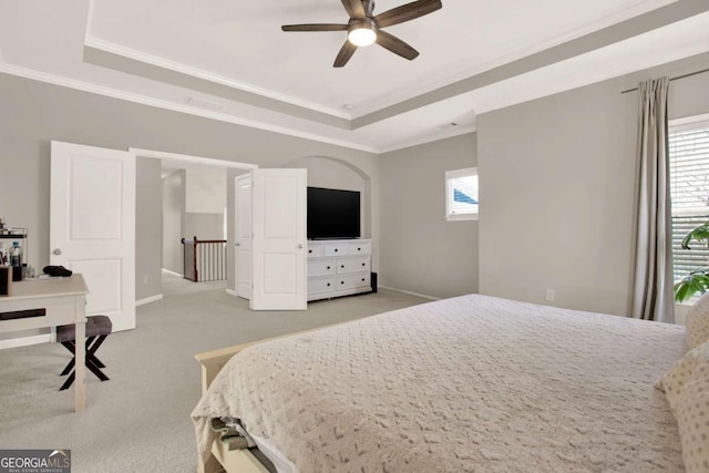 carpeted bedroom featuring crown molding, a ceiling fan, a raised ceiling, and baseboards