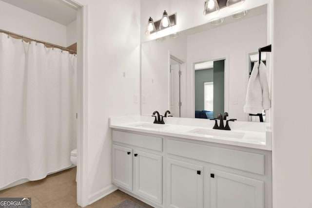 bathroom with double vanity, toilet, ensuite bathroom, and a sink