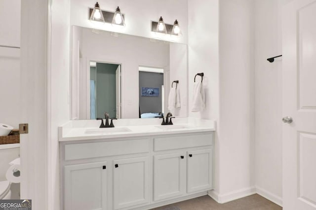 ensuite bathroom featuring ensuite bath, double vanity, toilet, and a sink