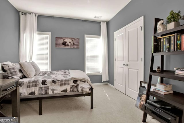 carpeted bedroom featuring baseboards, visible vents, and a closet