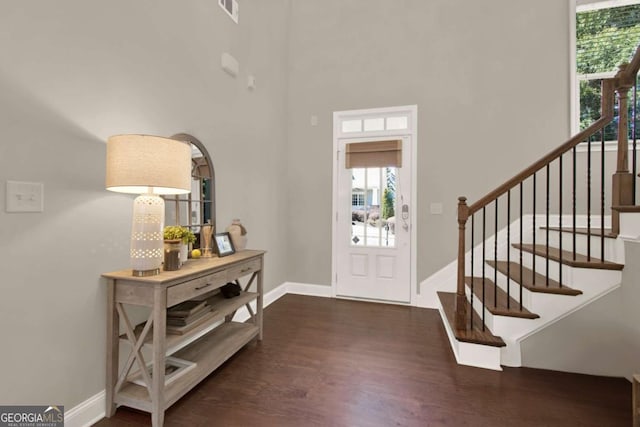 entryway featuring stairway, wood finished floors, visible vents, baseboards, and a high ceiling