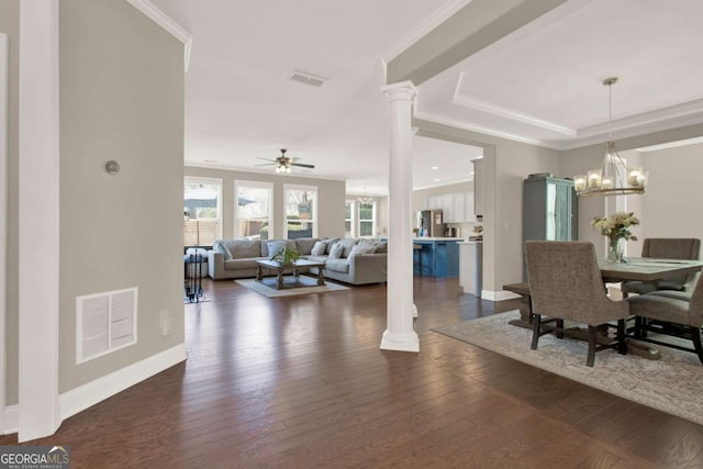 dining space with crown molding, ceiling fan with notable chandelier, visible vents, and dark wood-style flooring