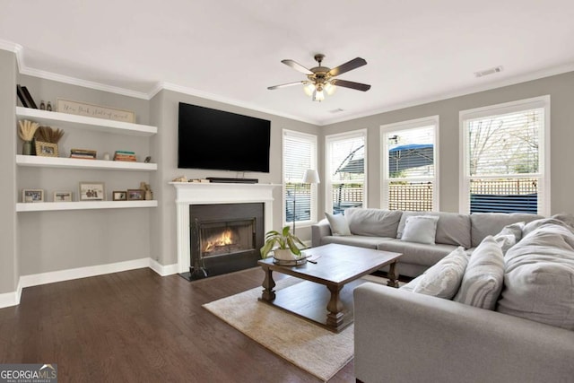 living room featuring a ceiling fan, visible vents, dark wood finished floors, a fireplace with flush hearth, and ornamental molding