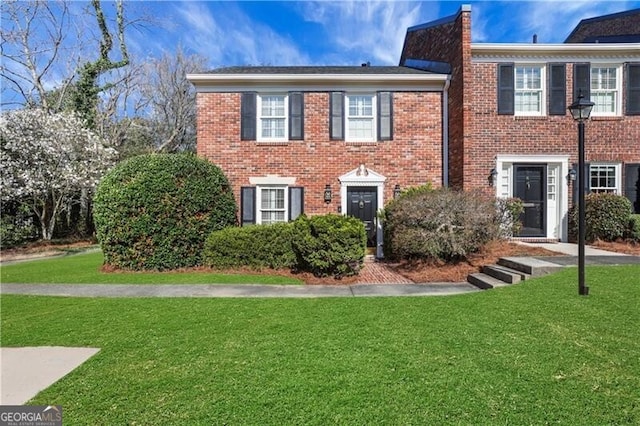 view of front facade with brick siding and a front lawn