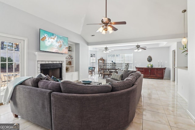 living room featuring built in features, light tile patterned floors, lofted ceiling, a fireplace, and ceiling fan