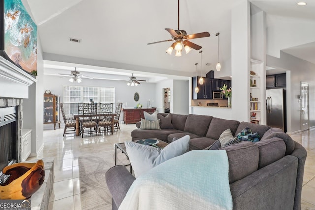 living room featuring visible vents, high vaulted ceiling, a fireplace, and a ceiling fan