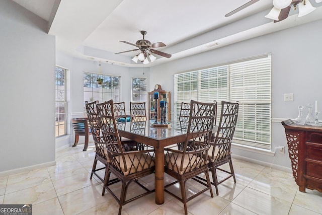 dining space with plenty of natural light, a raised ceiling, and ceiling fan