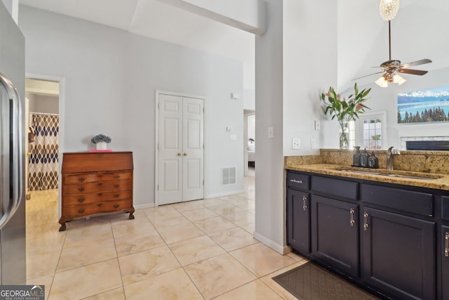 kitchen featuring visible vents, high vaulted ceiling, a ceiling fan, a sink, and light stone countertops