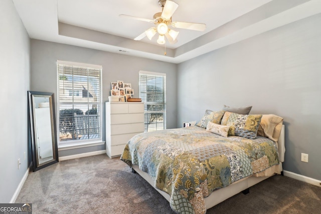 bedroom featuring a tray ceiling, a ceiling fan, baseboards, and carpet floors