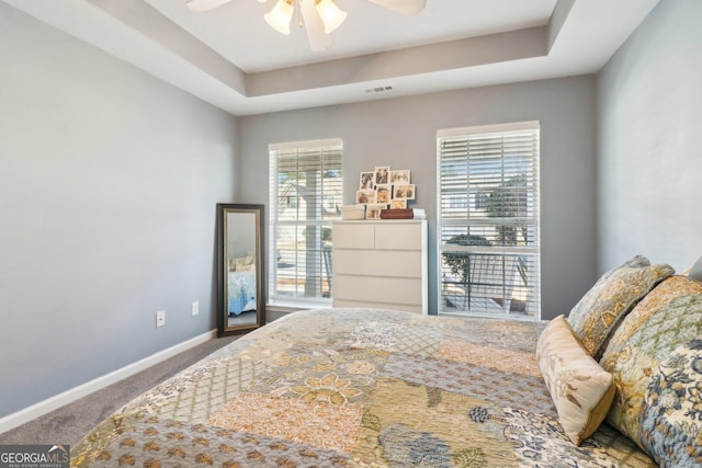 bedroom with visible vents, a ceiling fan, baseboards, carpet flooring, and a raised ceiling