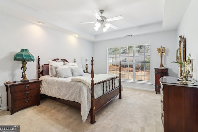 bedroom with light carpet, visible vents, baseboards, and a tray ceiling