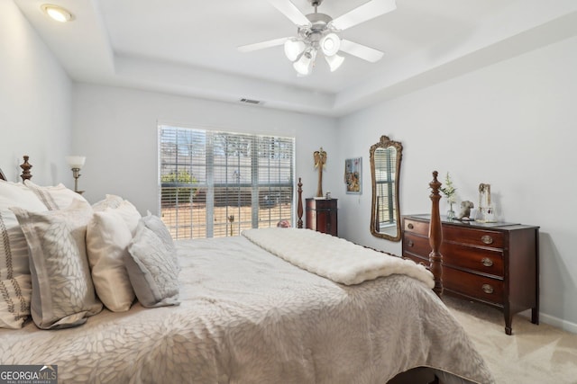 bedroom with visible vents, baseboards, light carpet, a raised ceiling, and a ceiling fan