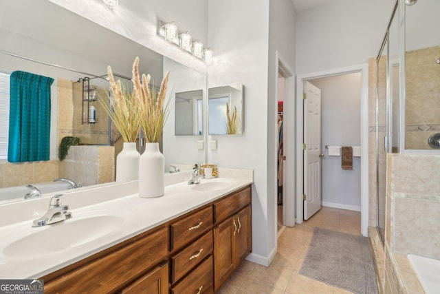 bathroom with a sink, a shower stall, tile patterned flooring, double vanity, and baseboards