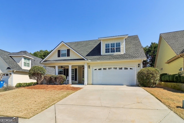 view of front facade featuring a ceiling fan, an attached garage, covered porch, a shingled roof, and concrete driveway