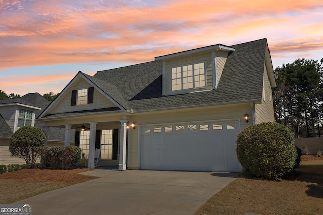 view of front of property featuring driveway, a shingled roof, a garage, and a ceiling fan