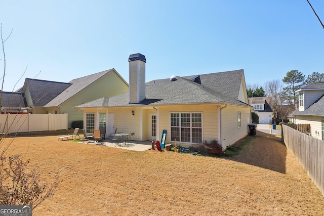 rear view of property featuring a fenced backyard, a lawn, a patio, and roof with shingles