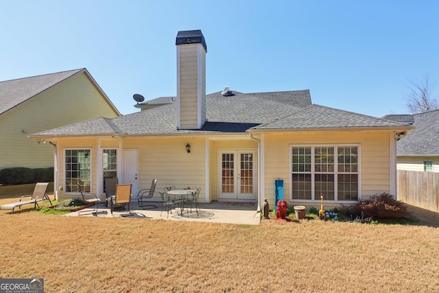 rear view of house featuring a lawn, a patio, fence, french doors, and roof with shingles