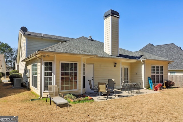 rear view of property featuring a patio, fence, central AC unit, a chimney, and a lawn