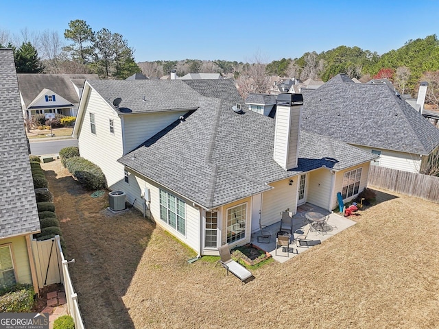 rear view of house with central AC, roof with shingles, a lawn, a fenced backyard, and a patio area