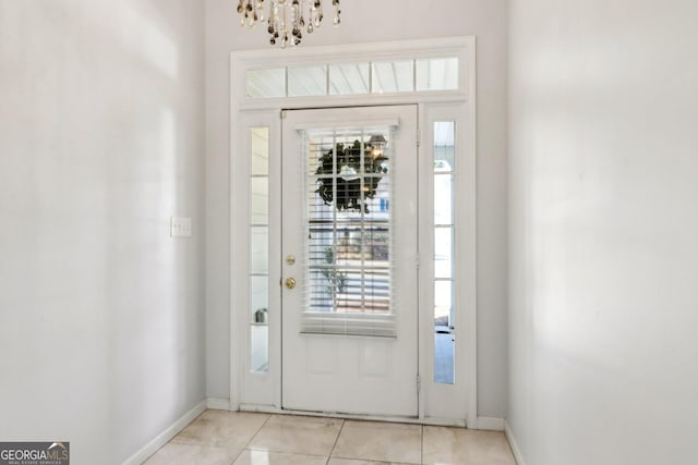 foyer featuring plenty of natural light, baseboards, light tile patterned floors, and a chandelier