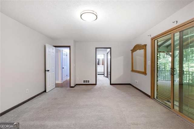 spare room featuring a textured ceiling, baseboards, visible vents, and light carpet