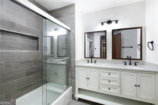 full bathroom featuring a sink, combined bath / shower with glass door, and double vanity