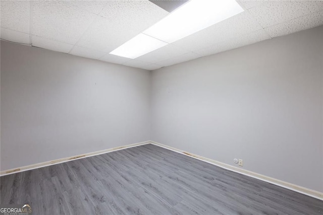 unfurnished room featuring a drop ceiling, baseboards, and wood finished floors