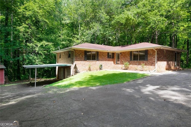 ranch-style home featuring brick siding, aphalt driveway, a carport, and a front lawn