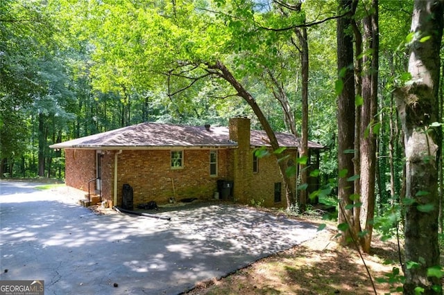 exterior space featuring brick siding and a wooded view