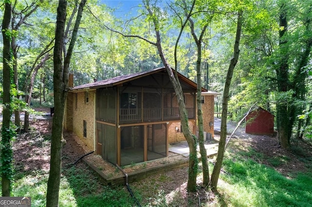 view of outdoor structure featuring a view of trees and a sunroom