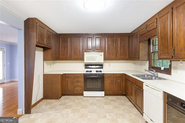 kitchen featuring a sink, white appliances, crown molding, light countertops, and baseboards