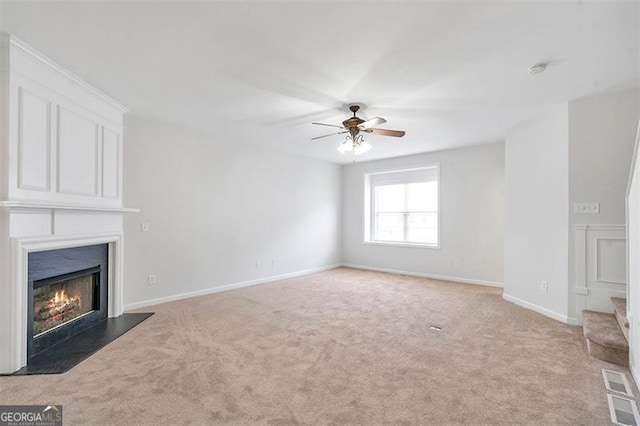 unfurnished living room with visible vents, light colored carpet, a large fireplace, and a ceiling fan