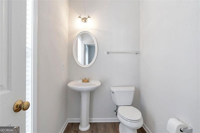 bathroom with toilet, baseboards, and wood finished floors