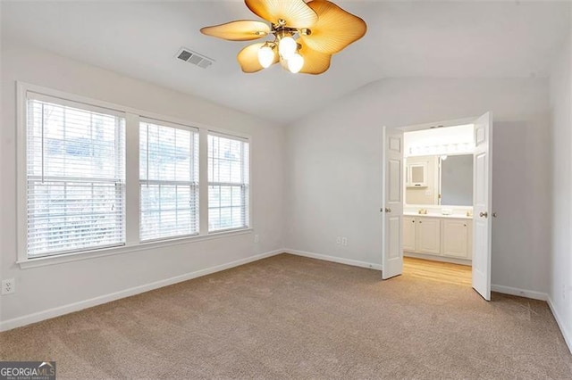 unfurnished bedroom with vaulted ceiling, baseboards, visible vents, and light carpet