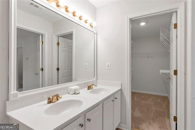 full bath featuring a sink, visible vents, a walk in closet, and double vanity