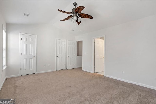 unfurnished bedroom with visible vents, baseboards, carpet, and multiple closets